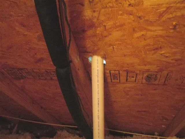 Plumbing vent pipe passing through the roof deck, seen from inside the attic