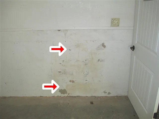 Water stains on a garage wall marked with red arrows