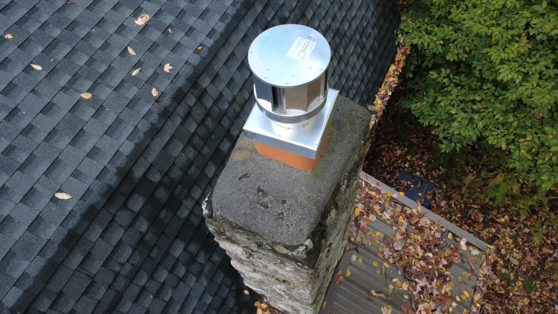 A chimney cap on a shingle roof